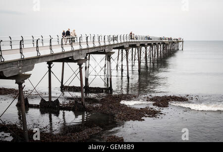 People walking on Saltburn`s Victorian pier with seaweed washing in at high tide. Saltburn, North Yorkshire, England. UK Stock Photo